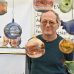 Jürgen Heintz hinter bunten Glaskugeln und -figuren