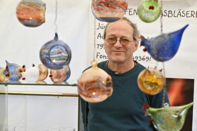 Jürgen Heintz hinter bunten Glaskugeln und -figuren