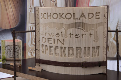 ein gefaltetes Buch mit eingraviertem Text: „Schokolade erweitert dein Speckdrum“