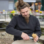 ein Mann arbeitet mit einer Zange an einem kleinen Besen
