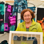 Gerda Müller-Häcker vor dunkler Kleidung mit geometrischen Formen in leuchtenden Farben