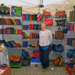 Lena Schmelzer vor einem Regal voller farbiger Ledertaschen
