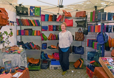Lena Schmelzer vor einem Regal voller farbiger Ledertaschen
