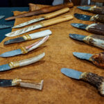 zwei Reihen Messer mit Feuerstein- und anderen Klingen sowie Griffen aus Horn, Knochen und Holz